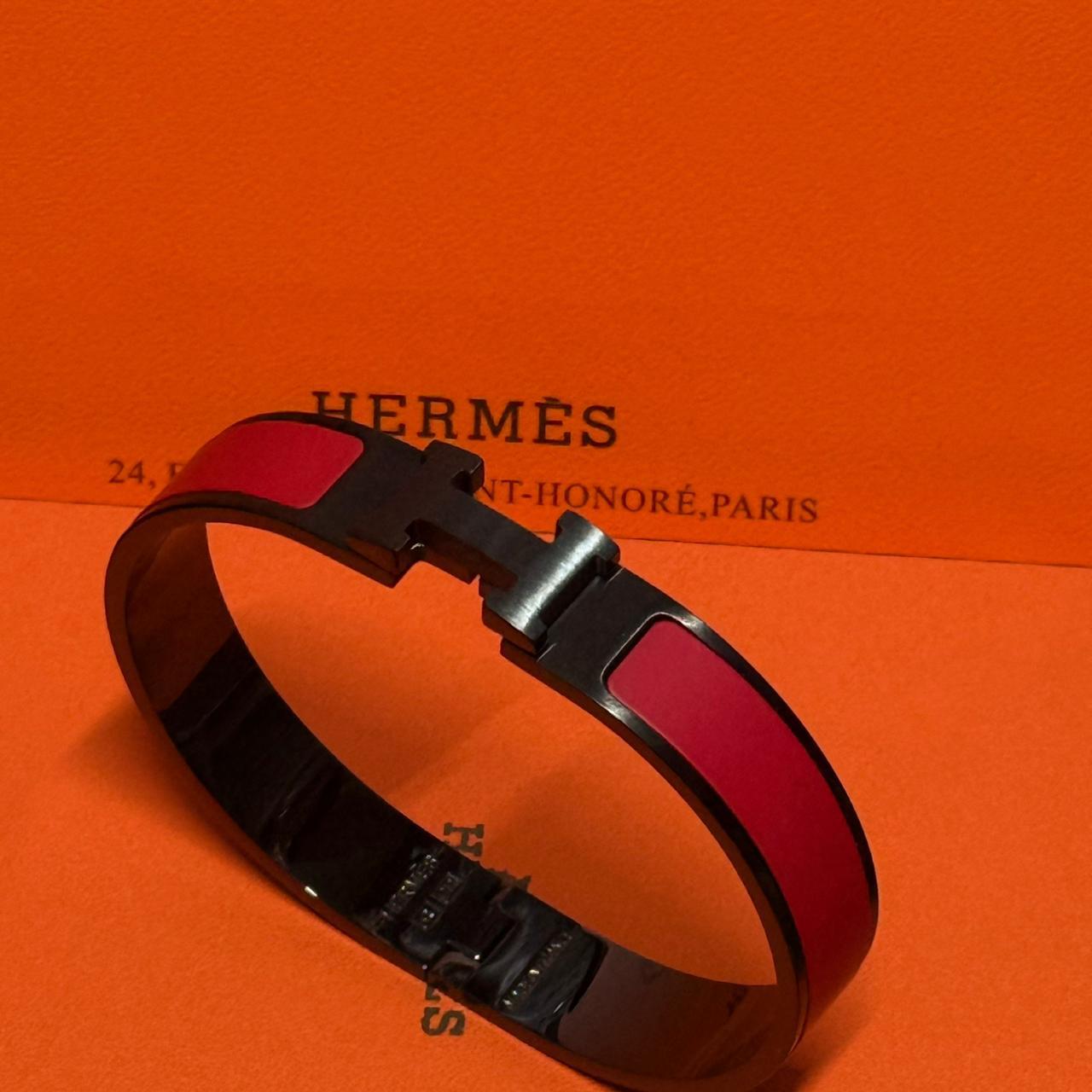 Hermes bracelet with red and black strap on an orange Hermès background