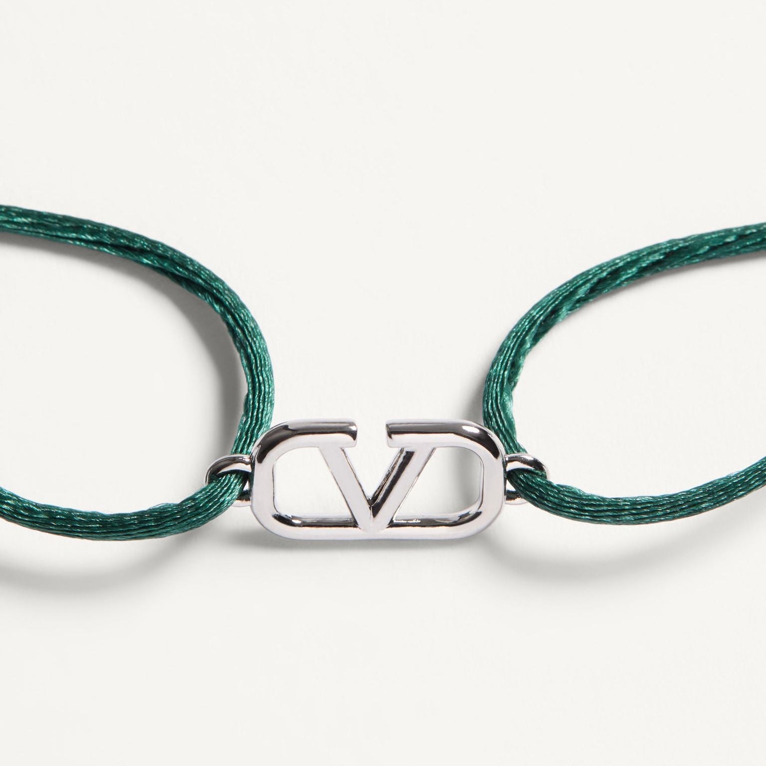 Green braided cord bracelet with a silver clasp on a white background