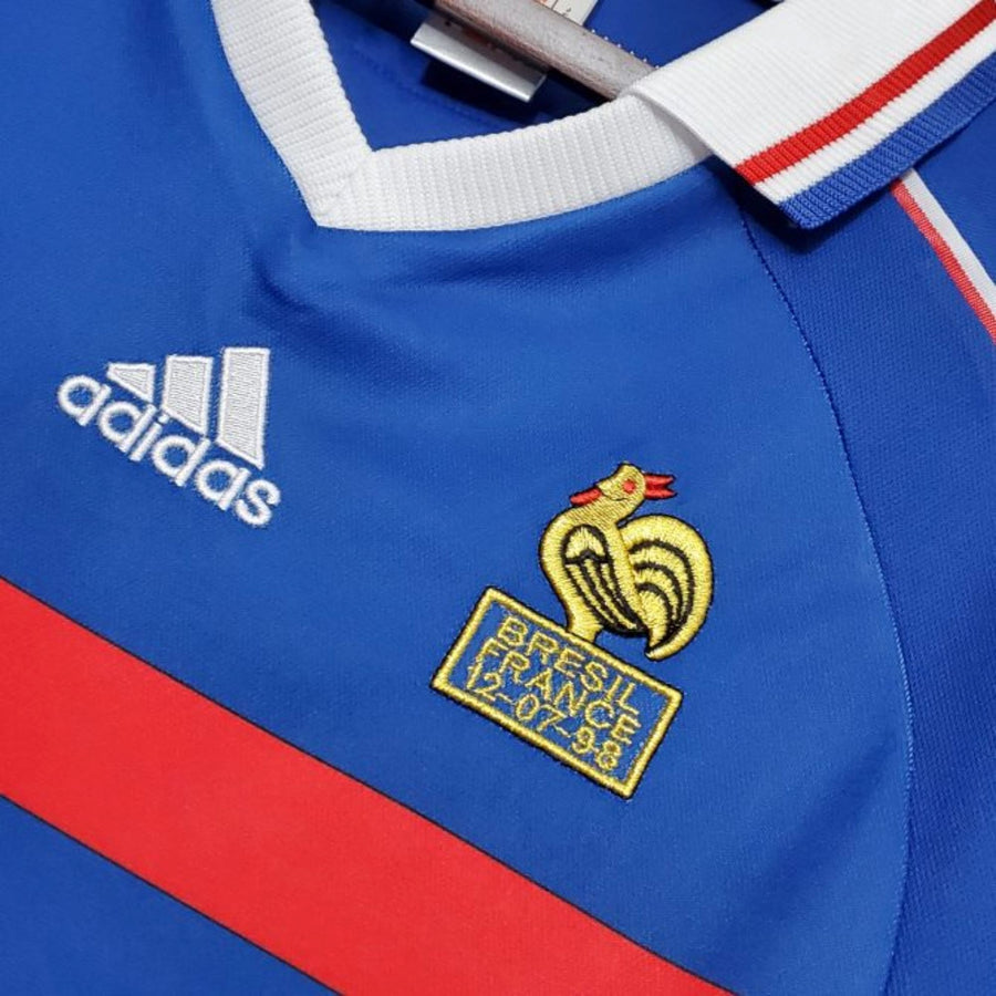 Close-up of a blue sports jersey with Adidas logo and embroidered badge.