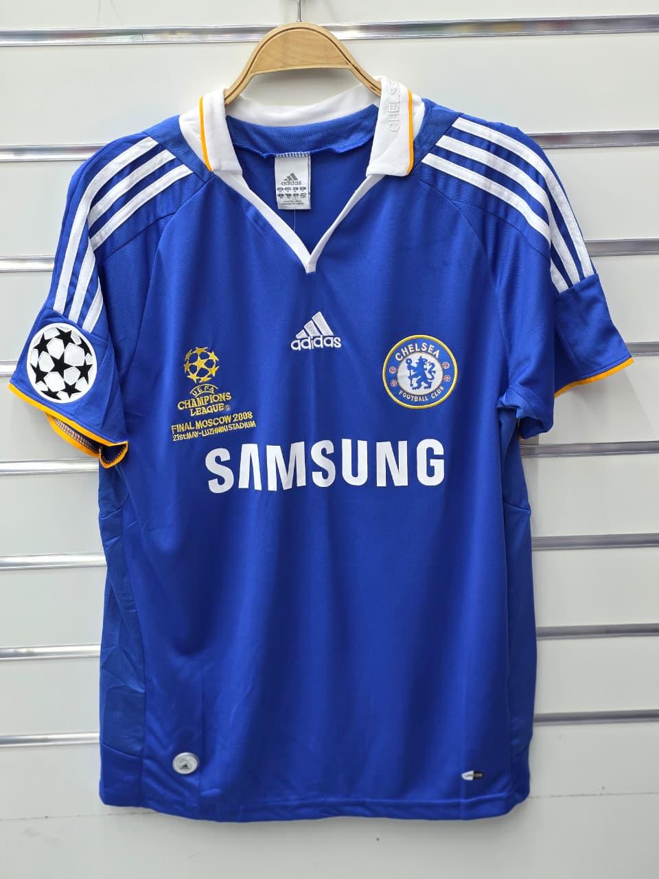 Blue sports jersey with Adidas, Chelsea, and Samsung logos on a hanger against a striped background