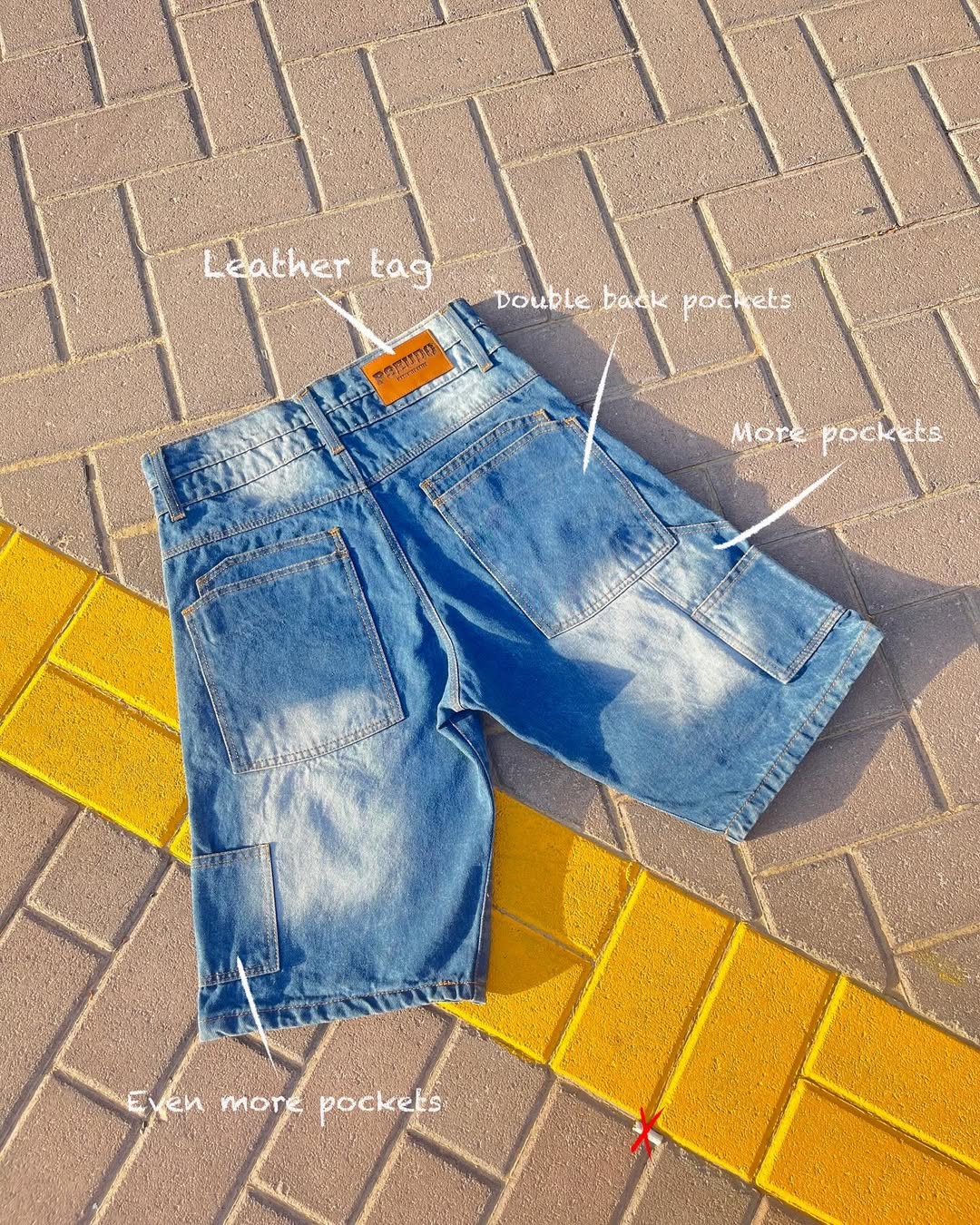Blue denim shorts on a paved surface with text labels pointing out features.