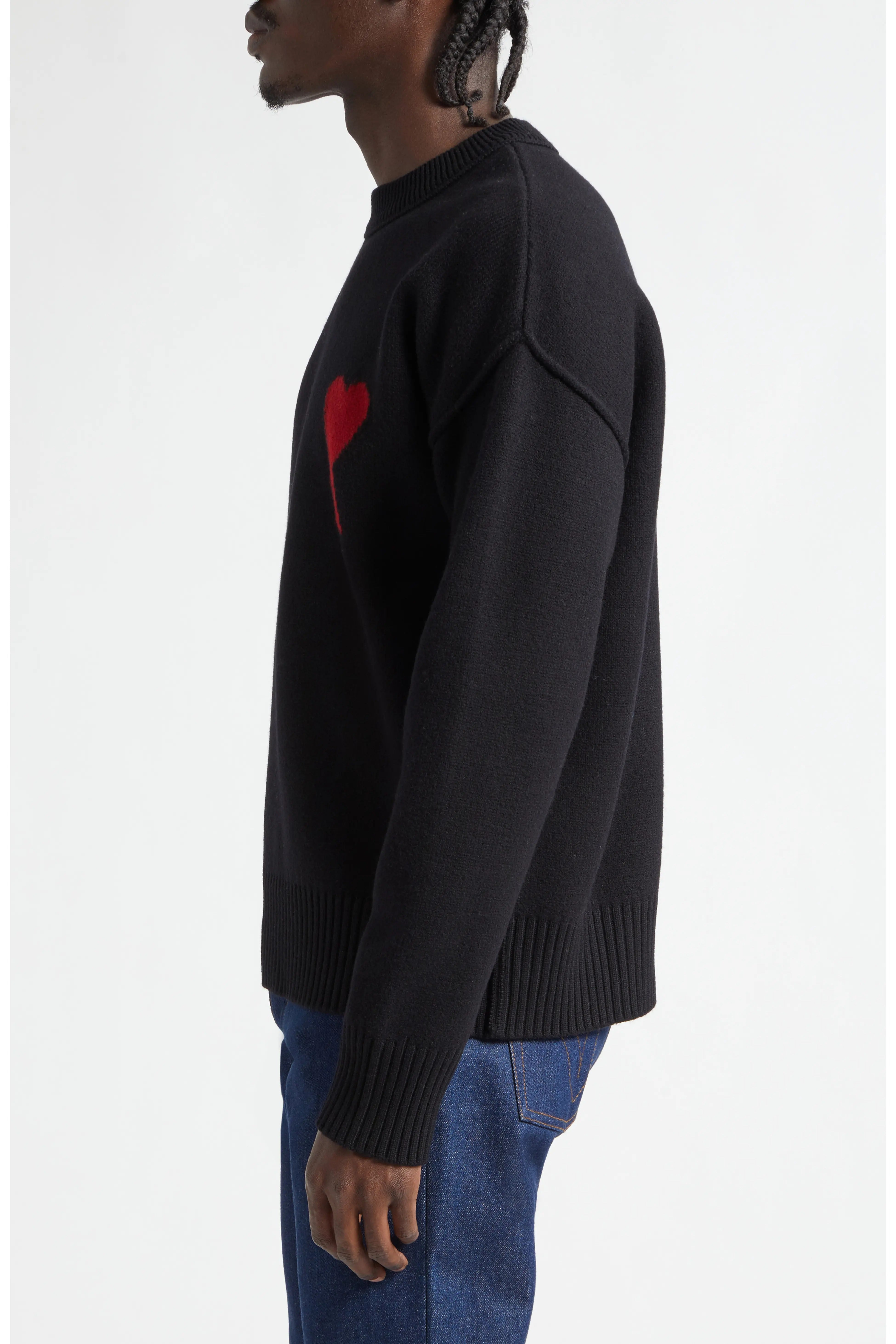 Person wearing a black sweater with a red heart design on a white background