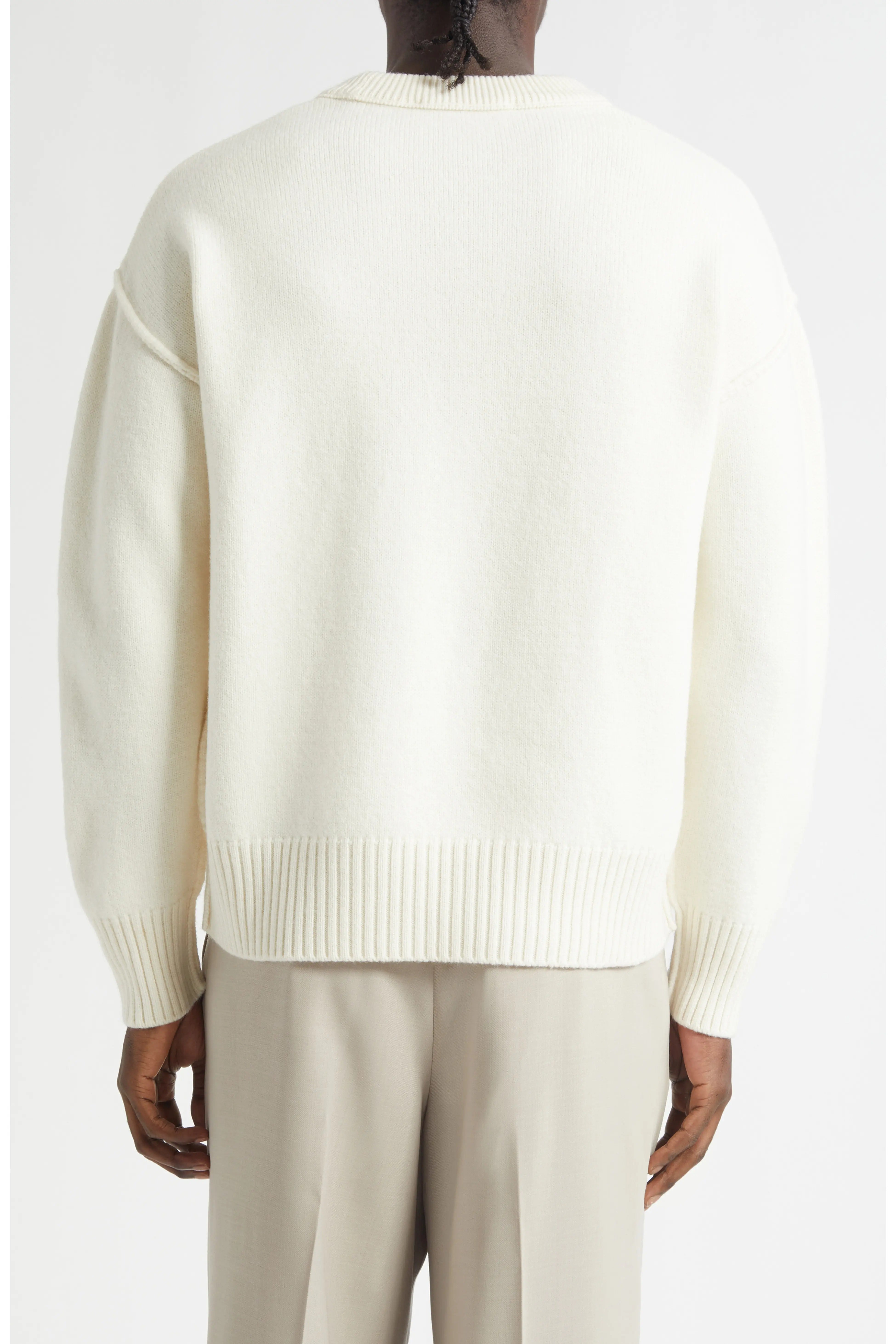 Person wearing a cream sweater and beige pants on a white background