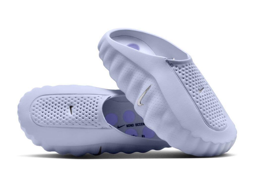 Pair of light purple Nike slides on a white background