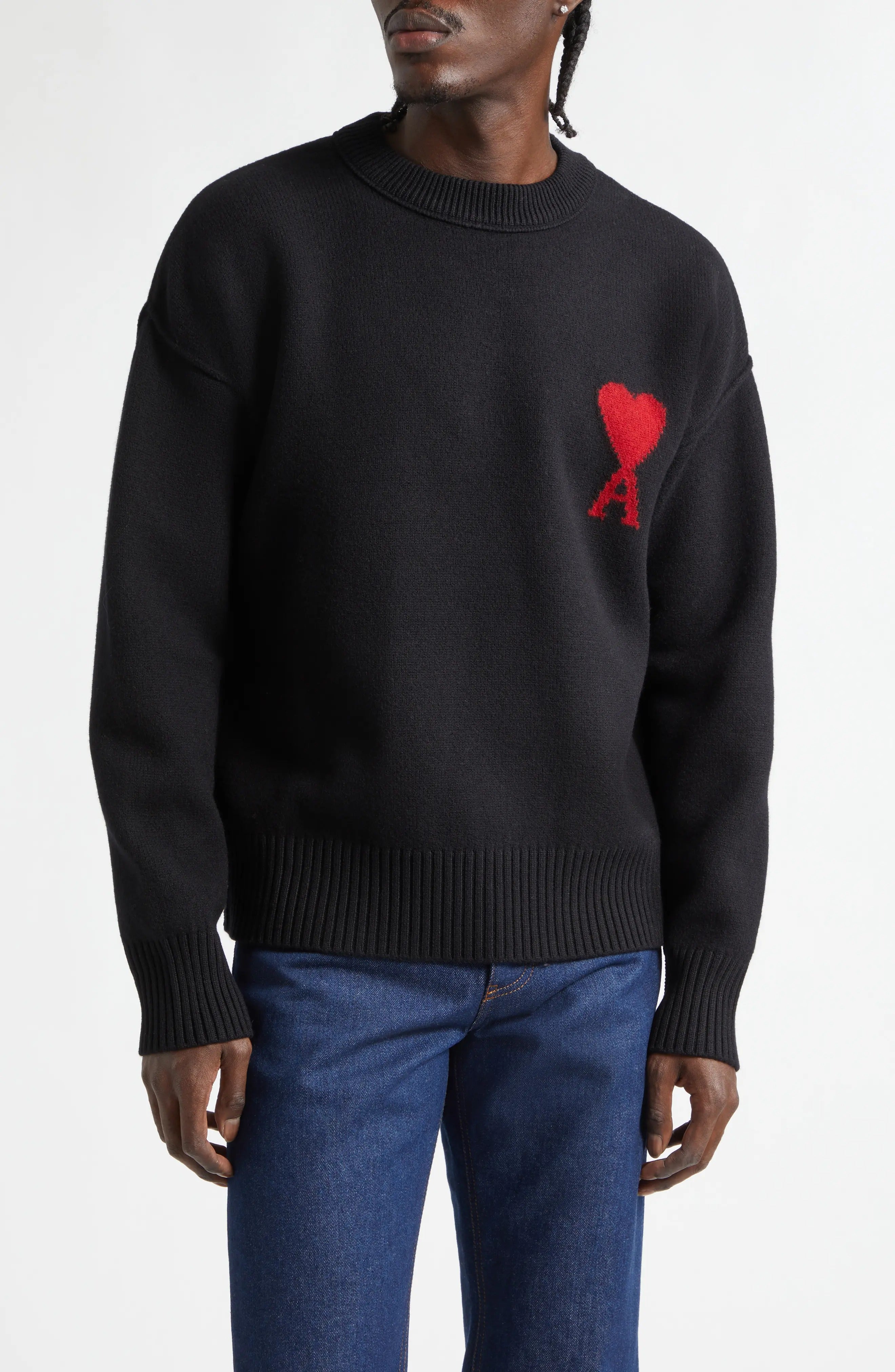 Person wearing a black sweater with a red heart design on a white background