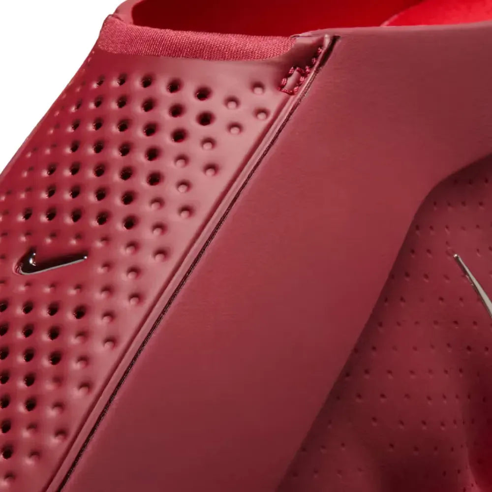 Close-up of a red sneaker with perforated design and Nike logo.